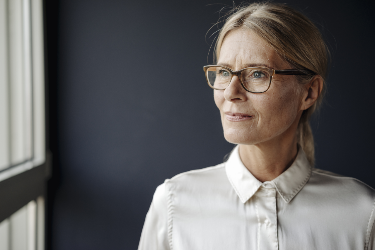 frau_mit_brille_schaut_aus_fenster_1280px